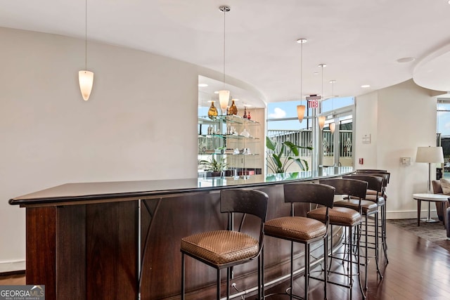 bar with dark wood-type flooring and hanging light fixtures