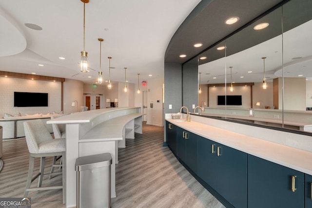 kitchen featuring pendant lighting, a spacious island, blue cabinets, and light wood-type flooring