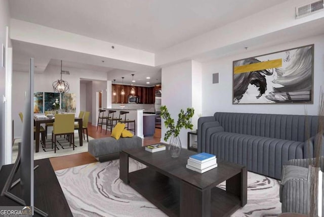 living room with an inviting chandelier and light hardwood / wood-style flooring