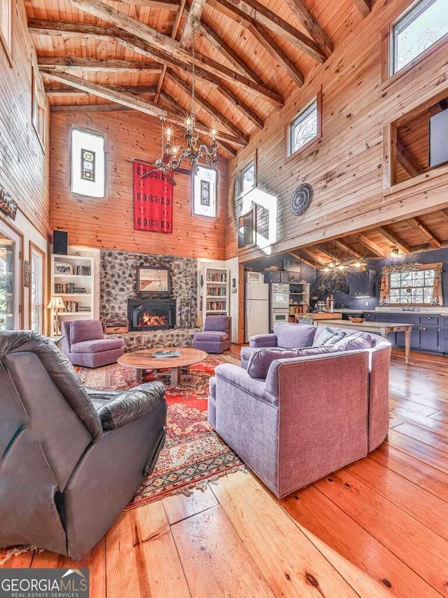 living room with a wood stove, plenty of natural light, high vaulted ceiling, and a chandelier