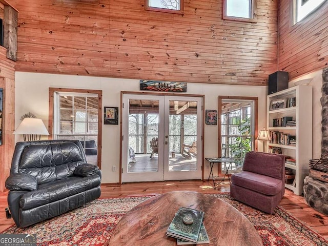 living room with french doors, light hardwood / wood-style floors, wooden ceiling, and a high ceiling