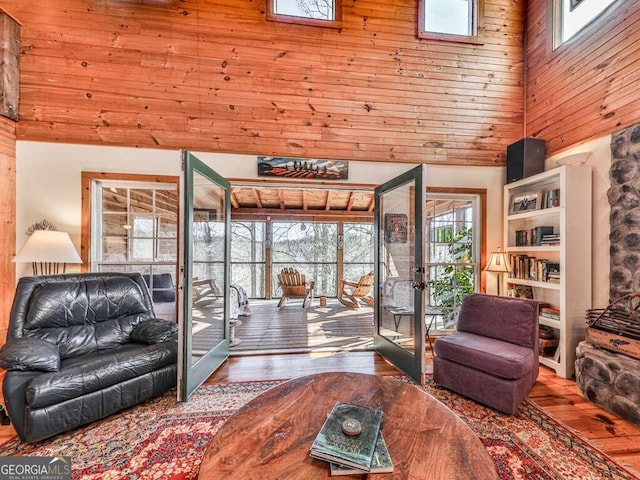 living room featuring hardwood / wood-style flooring, wooden walls, a high ceiling, and french doors