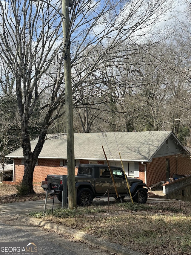 view of property exterior with brick siding and a shingled roof