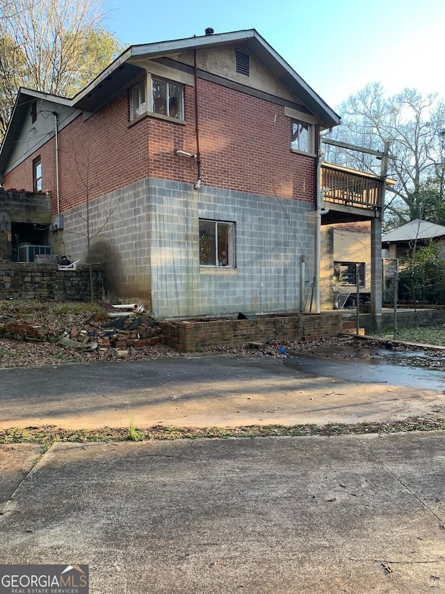 view of side of property featuring brick siding and a deck