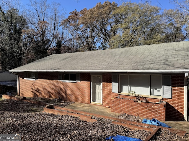 ranch-style home featuring brick siding and roof with shingles