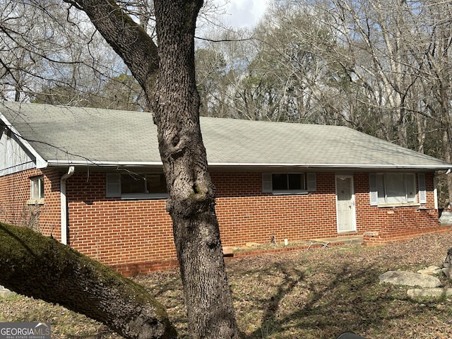 view of front facade with brick siding and roof with shingles