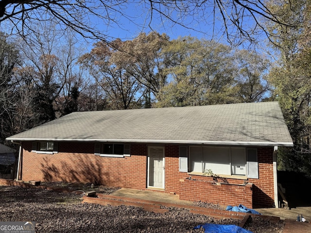 single story home featuring a shingled roof and brick siding