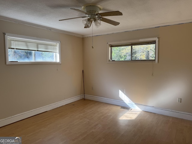 empty room featuring visible vents, ceiling fan, baseboards, light wood-type flooring, and a textured ceiling