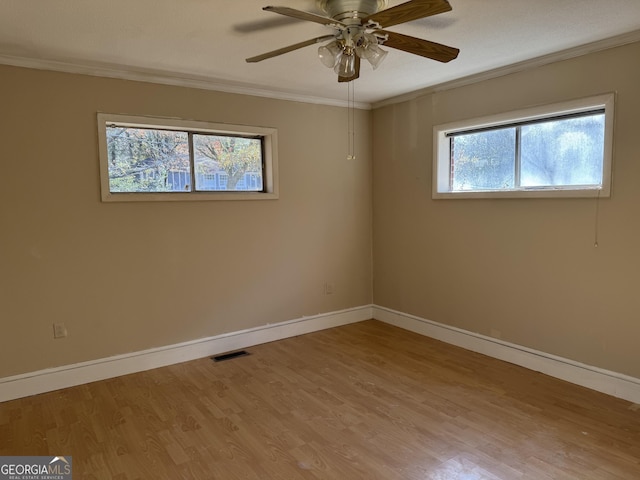 spare room featuring visible vents, baseboards, wood finished floors, and crown molding