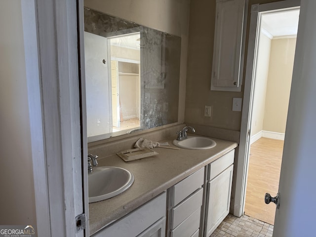 bathroom with double vanity, baseboards, and a sink