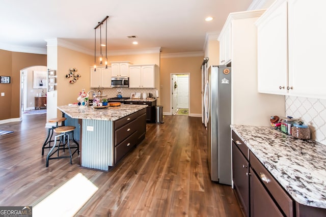 kitchen with white cabinets, appliances with stainless steel finishes, dark hardwood / wood-style flooring, and decorative light fixtures