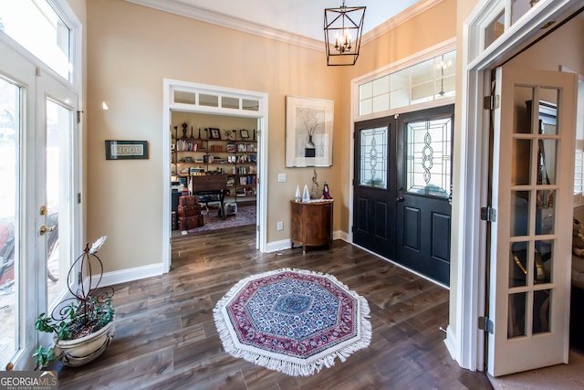 foyer featuring dark hardwood / wood-style flooring, an inviting chandelier, and ornamental molding