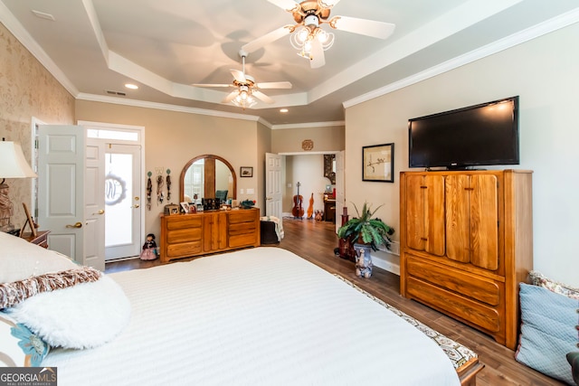 bedroom with hardwood / wood-style flooring, ceiling fan, crown molding, and a tray ceiling