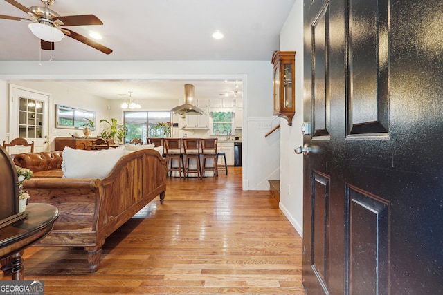 entryway with light hardwood / wood-style flooring, ceiling fan with notable chandelier, and sink