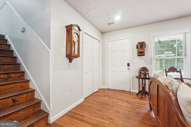 foyer entrance featuring a textured ceiling and light wood-type flooring