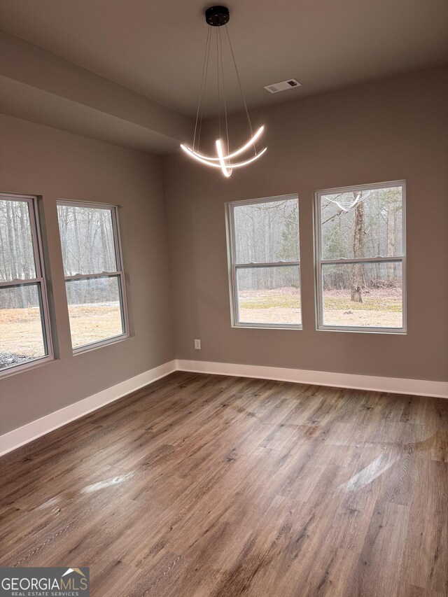 unfurnished room featuring an inviting chandelier and hardwood / wood-style floors