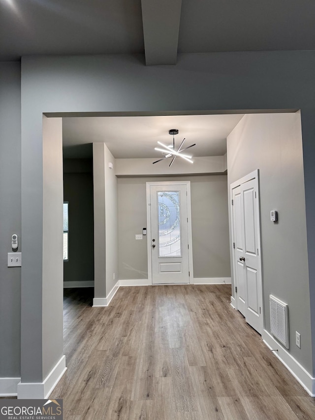 foyer with light wood-type flooring and a notable chandelier