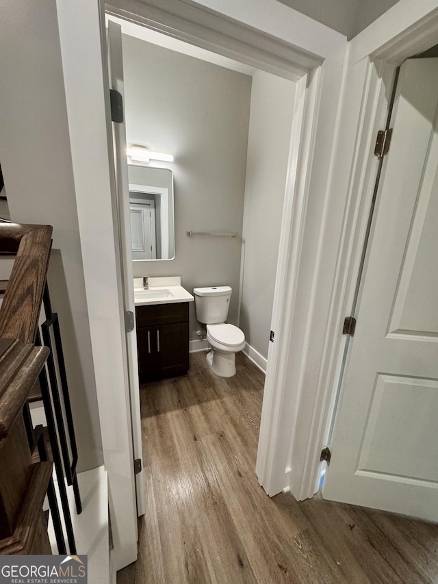 bathroom featuring wood-type flooring, toilet, and vanity