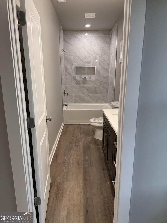 full bathroom with toilet, vanity, tiled shower / bath, and hardwood / wood-style flooring