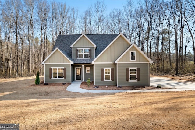 craftsman house with dirt driveway, board and batten siding, and roof with shingles