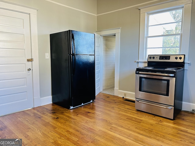 kitchen with stainless steel electric stove, black fridge, and light hardwood / wood-style flooring