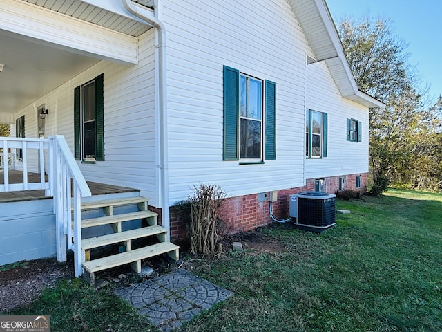 view of side of property featuring central AC unit and a lawn