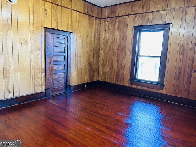 unfurnished room featuring wood walls and dark wood-type flooring