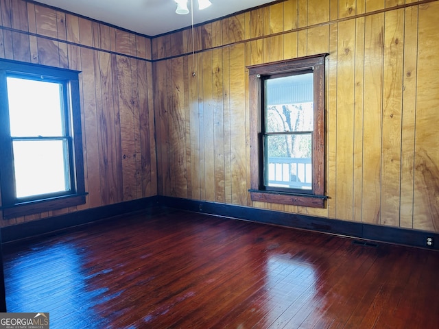 spare room featuring wood walls and dark hardwood / wood-style flooring