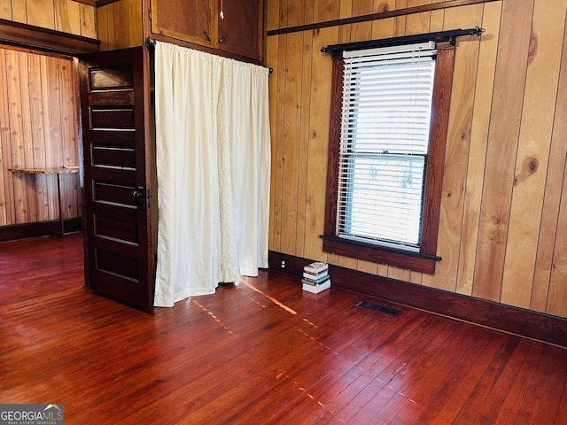 unfurnished bedroom featuring wood walls and dark wood-type flooring