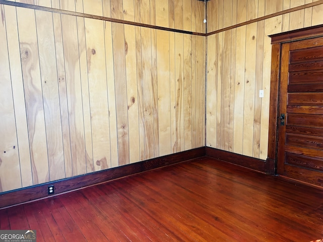 spare room featuring wooden walls and dark hardwood / wood-style floors