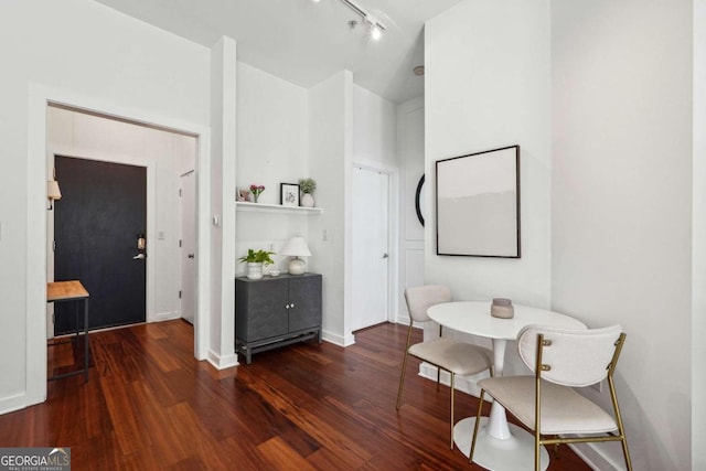 dining space with dark hardwood / wood-style floors and rail lighting