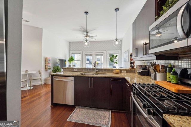 kitchen with stainless steel appliances, dark wood finished floors, a sink, and dark brown cabinets