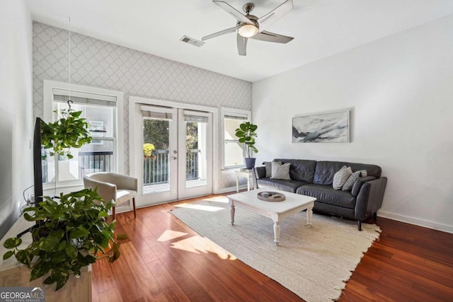 living area with wallpapered walls, visible vents, dark wood finished floors, and french doors