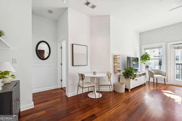 sitting room featuring dark wood-style flooring, visible vents, baseboards, and wallpapered walls