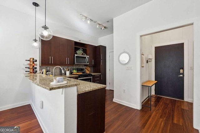 kitchen featuring dark brown cabinetry, light stone countertops, kitchen peninsula, decorative light fixtures, and appliances with stainless steel finishes