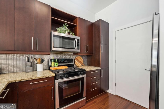 kitchen with dark brown cabinetry, light stone countertops, dark hardwood / wood-style flooring, backsplash, and appliances with stainless steel finishes