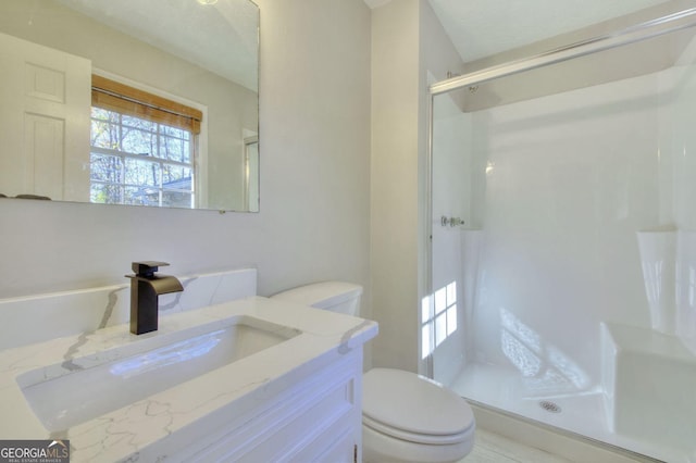 bathroom with vanity, toilet, a shower with shower door, and a textured ceiling