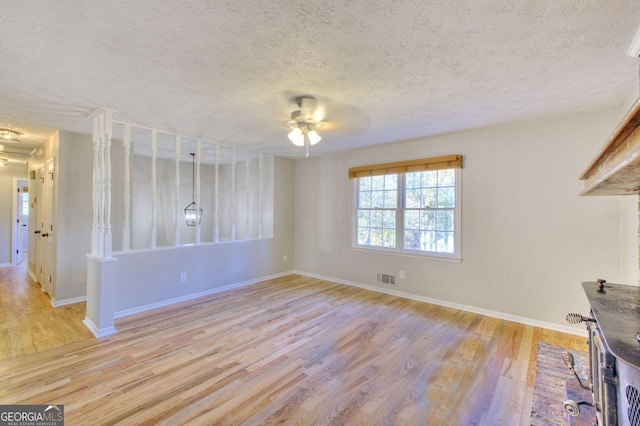 spare room with ceiling fan, light hardwood / wood-style flooring, and a textured ceiling