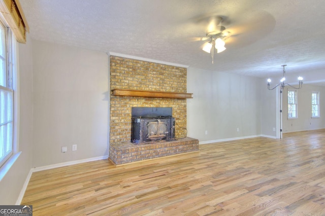 unfurnished living room with ceiling fan with notable chandelier, hardwood / wood-style floors, a textured ceiling, and plenty of natural light