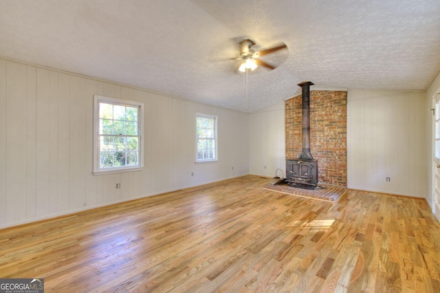 1304 Vine St NE, Gainesville, GA 30501 - unfurnished living room featuring a textured ceiling, a ceiling fan, wood finished floors, a wood stove, and vaulted ceiling