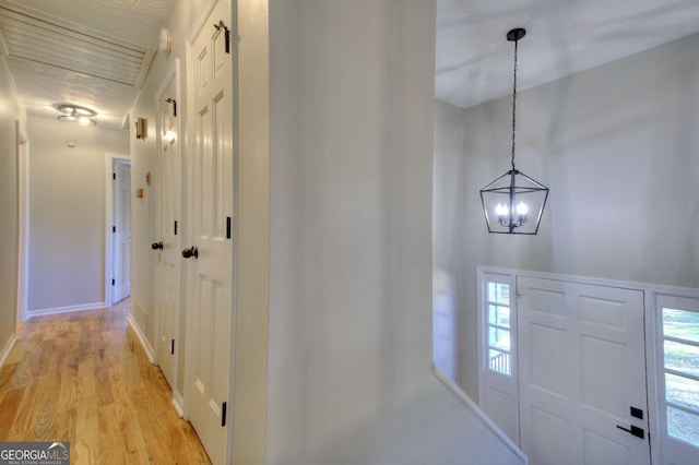 corridor featuring a chandelier, a textured ceiling, and light hardwood / wood-style flooring