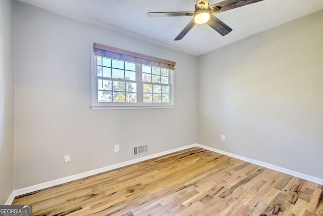 empty room with a textured ceiling, light wood-type flooring, and ceiling fan