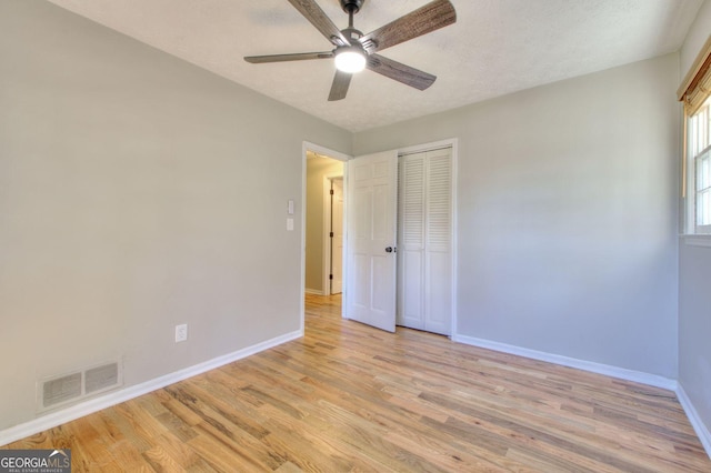 unfurnished bedroom with a textured ceiling, a closet, light hardwood / wood-style flooring, and ceiling fan