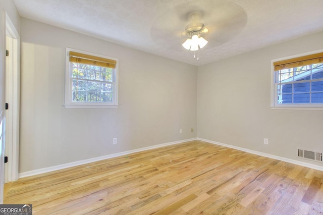 unfurnished room with ceiling fan, a textured ceiling, and light wood-type flooring