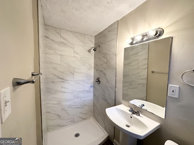 bathroom featuring tiled shower, a textured ceiling, and sink