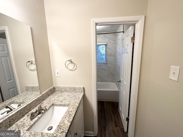 bathroom with vanity, wood-type flooring, and tiled shower / bath combo