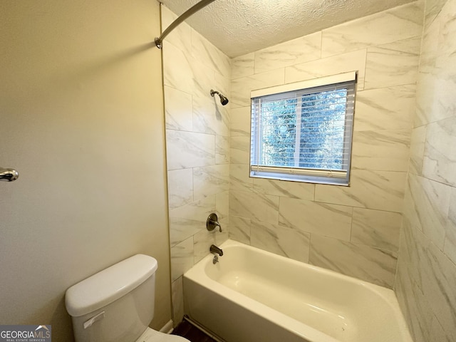 bathroom featuring toilet, a textured ceiling, and tiled shower / bath combo