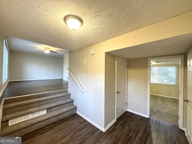 stairs featuring a textured ceiling, hardwood / wood-style flooring, and ceiling fan