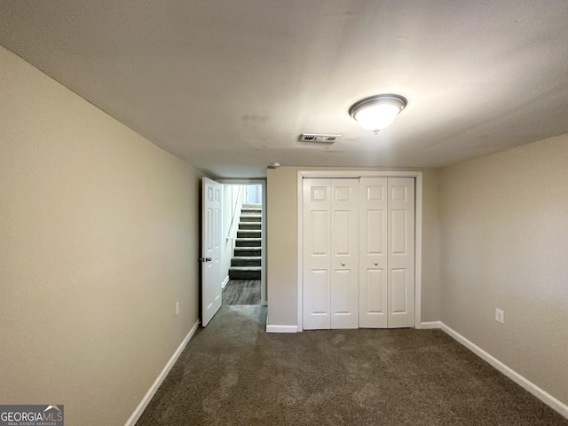 unfurnished bedroom featuring dark colored carpet and a closet