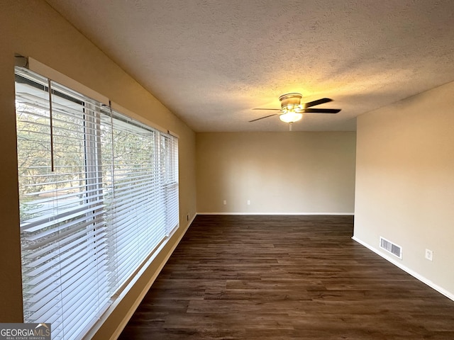 empty room with a textured ceiling, dark hardwood / wood-style floors, and ceiling fan